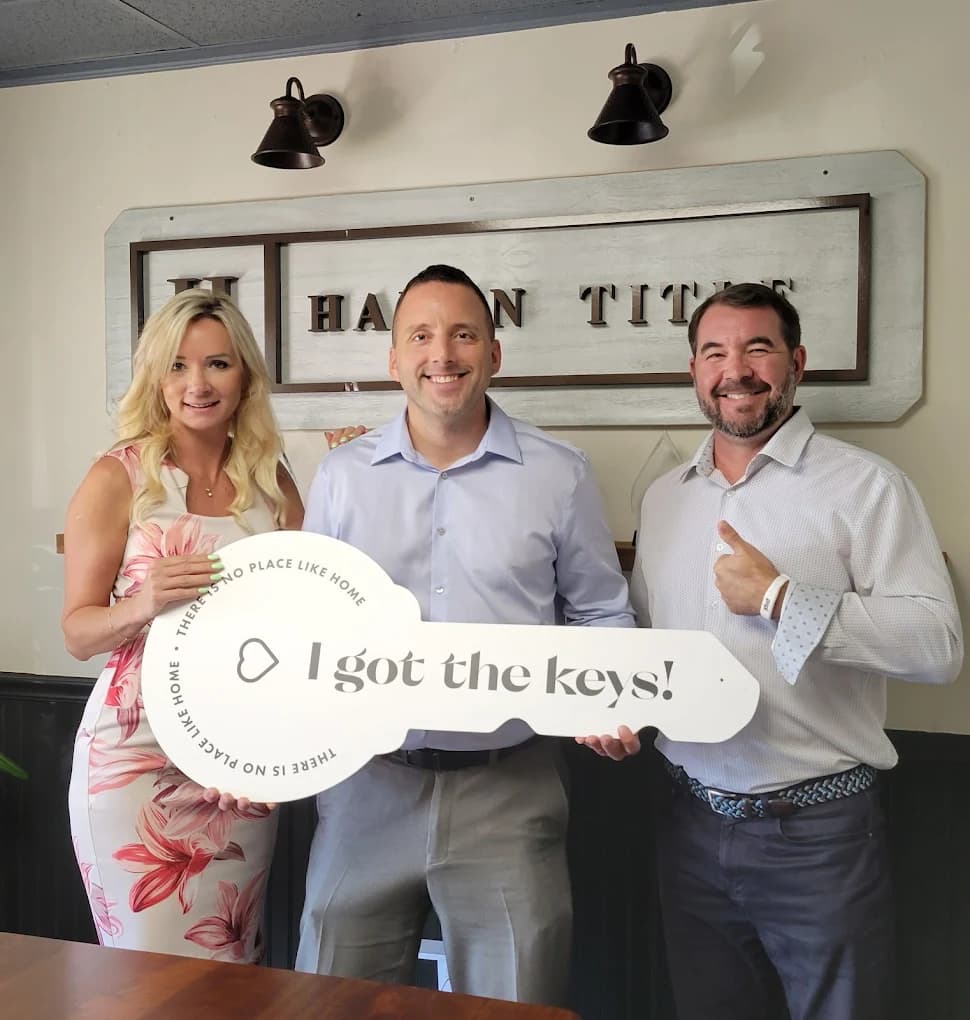 Happy buyers holding an oversized house key on closing day